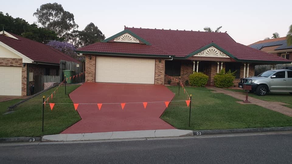 Brick home with a freshly stained deep red paver driveway and path