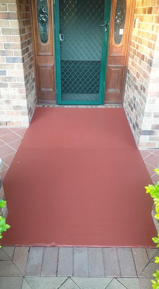 Front entry porch freshly coated in terracotta red leading to a timber door