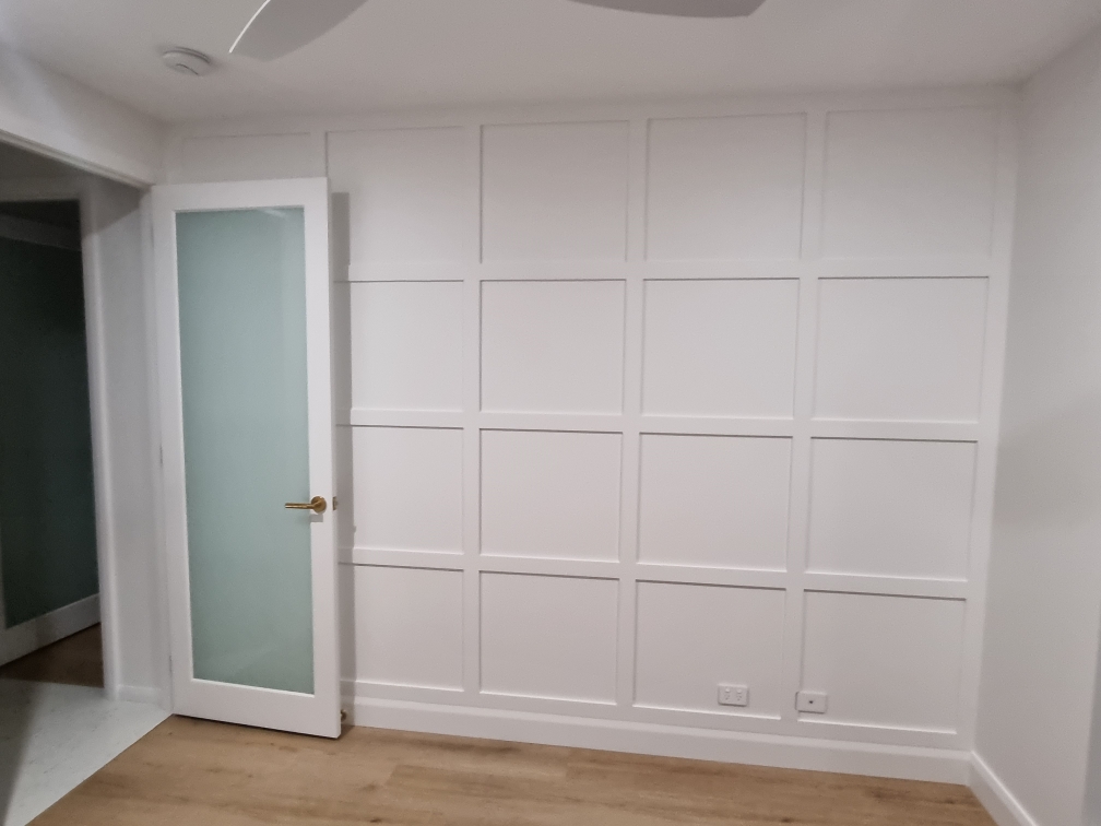 White panelled feature wall with a frosted glass door and timber floor