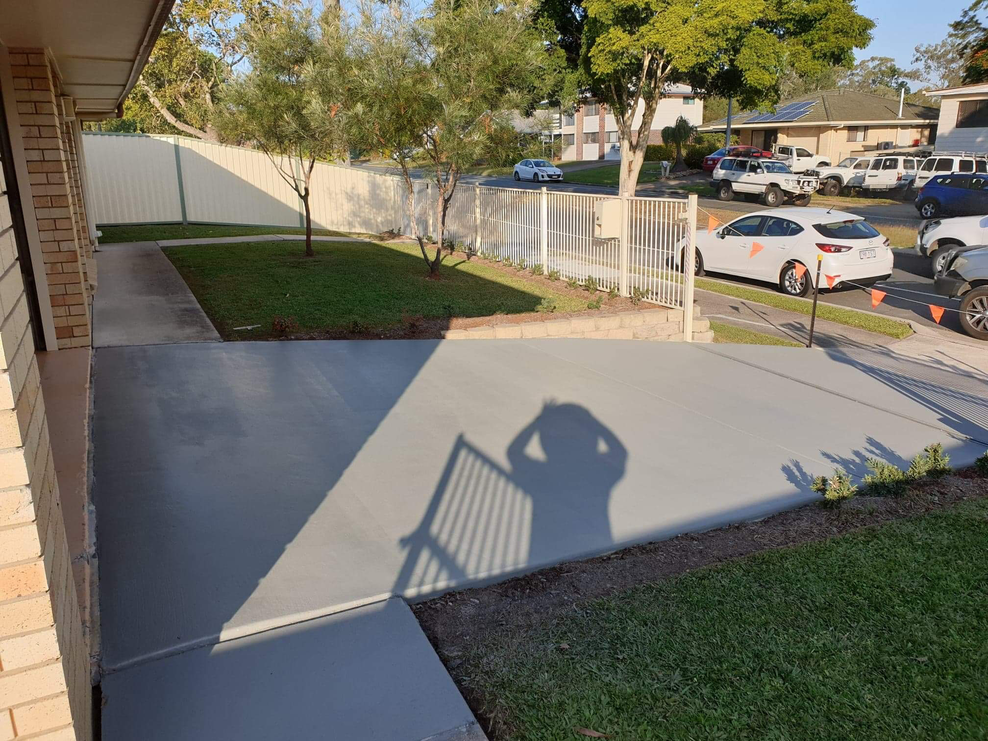 Freshly coated grey concrete driveway beside a brick house