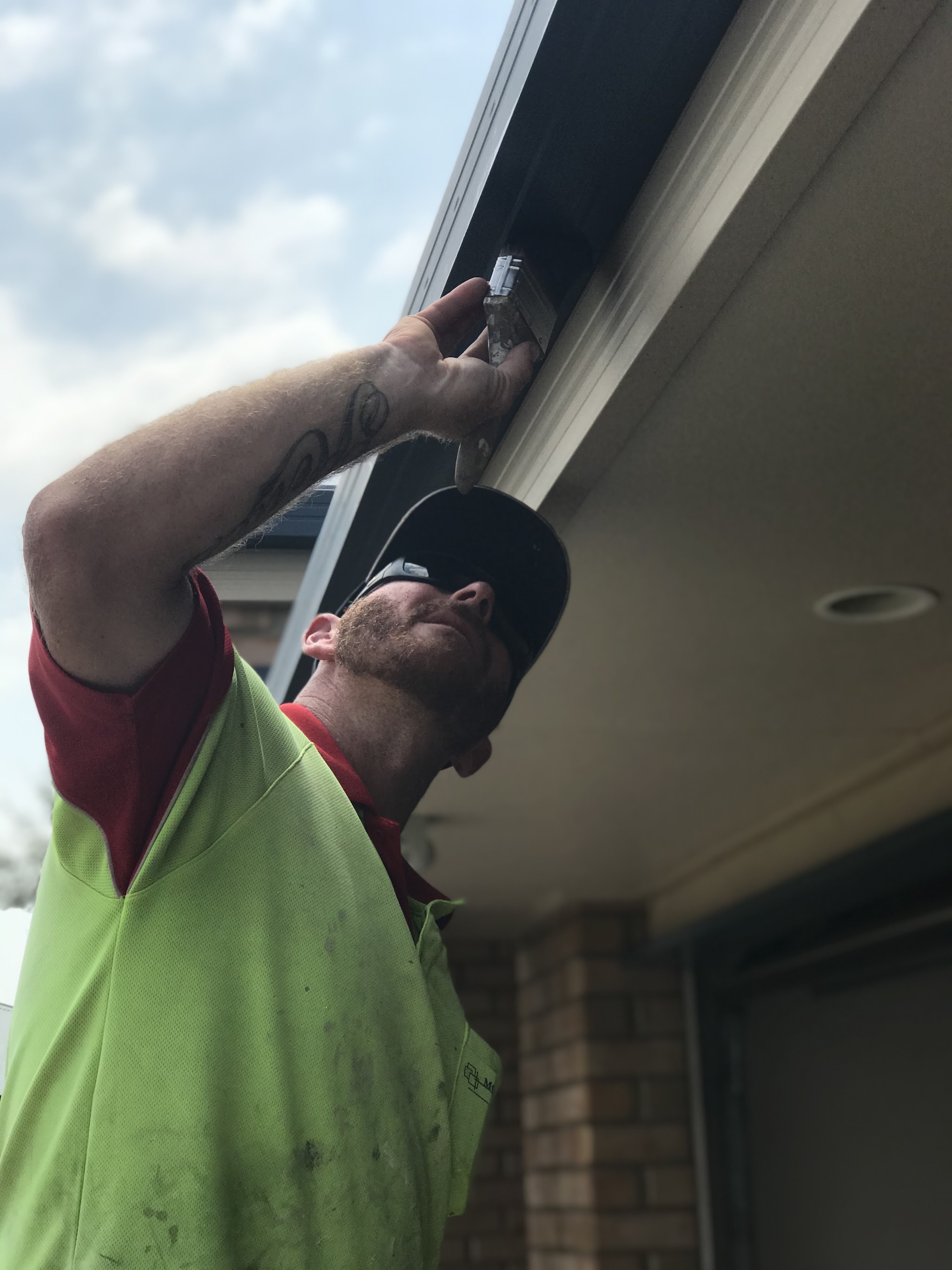 Scott cutting in paint under the eaves with a brush